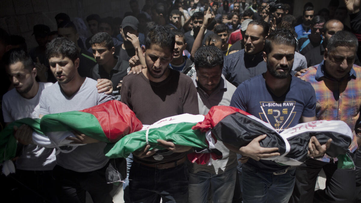 Palestinian mourners carry the bodies of three children were killed in a fire caused by candle sparked on their family house.