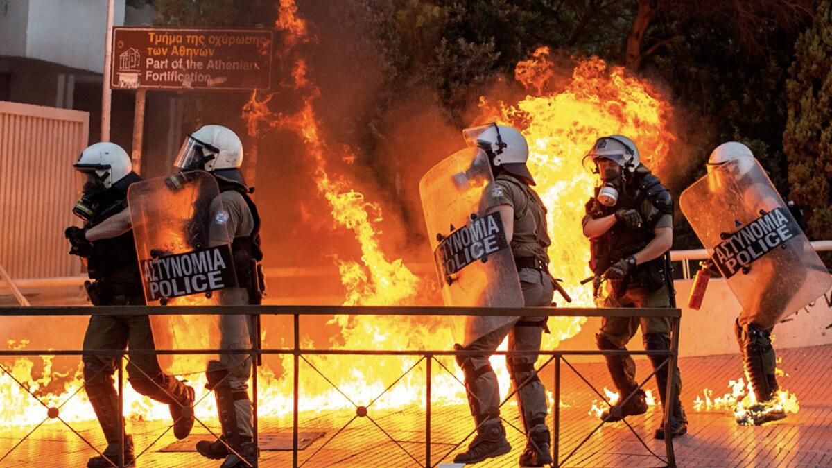 Riot police officers try to avoid patrol bombs thrown by protesters outside the Greek Parliament during a demonstration against a new law on protest rules in Athens, Greece. Photo: AFP
