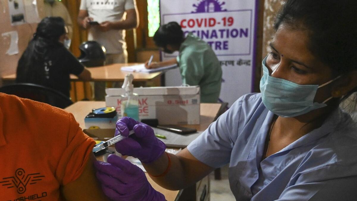 A health worker inoculates a man with a dose of the Covishield vaccine against the Covid-19 coronavirus inside a vaccination centre in Ghaziabad on October 20, 2021. (Photo by Prakash SINGH / AFP)