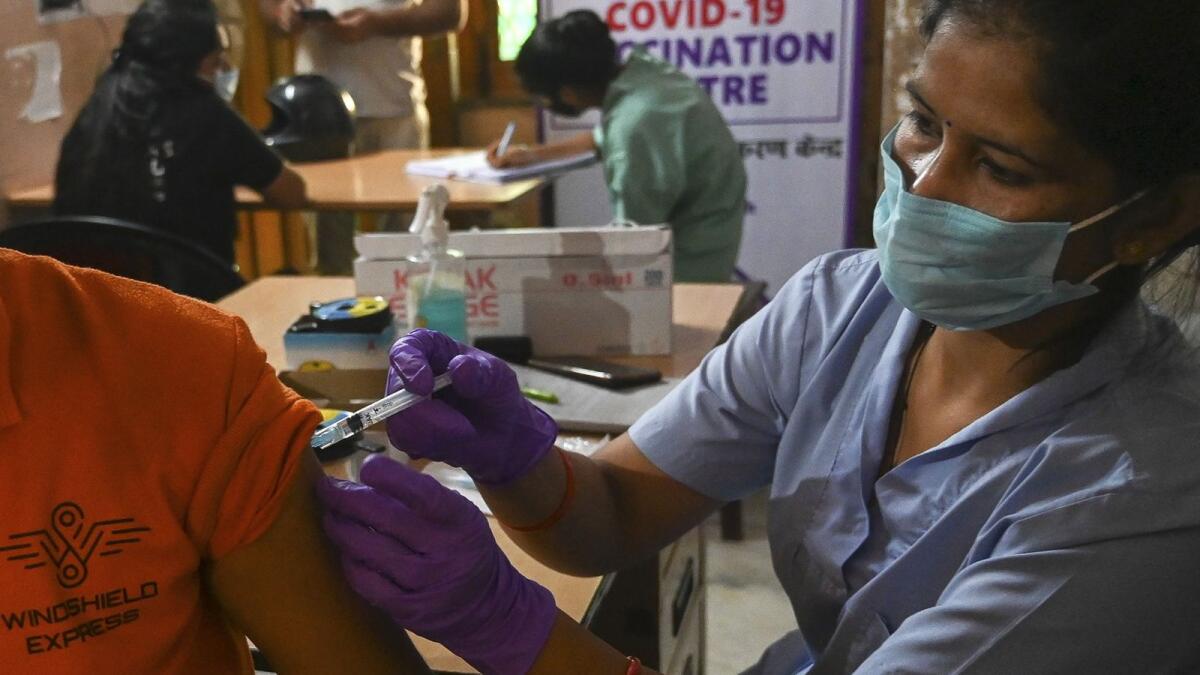 A health worker inoculates a man with a dose of the Covishield vaccine against the Covid-19 coronavirus inside a vaccination centre in Ghaziabad on October 20, 2021. (Photo by Prakash SINGH / AFP)