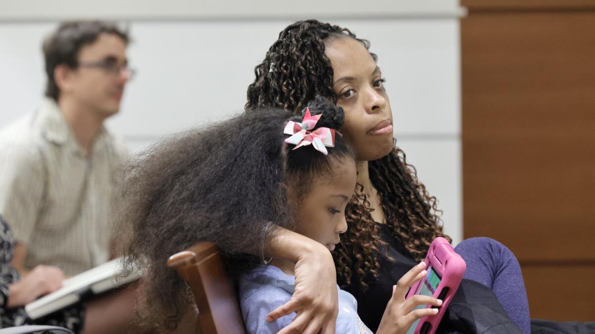 Philana Holmes and her daughter Olivia Caraballo, 7 listen to the final witness in their case at the Broward County Courthouse in Fort Lauderdale on May 10, 2023. — AP