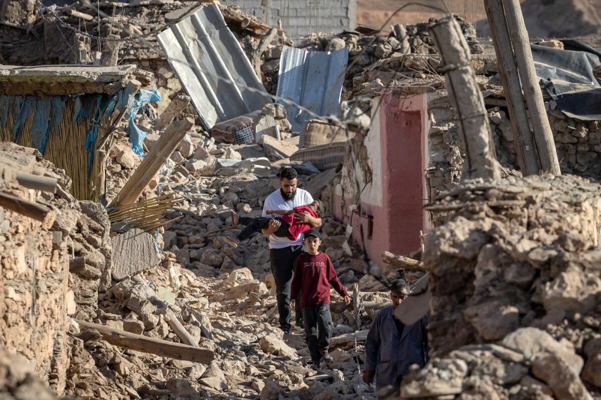 People walk past destroyed houses after an earthquake in the mountain village of Tafeghaghte, southwest of the city of Marrakesh, on September 9, 2023. — AFP