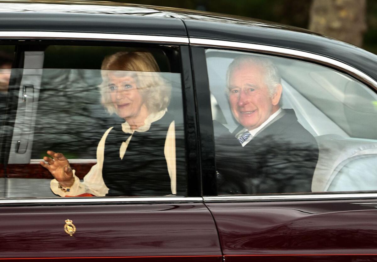 Britain's King Charles III and Britain's Queen Camilla wave as they leave by car from Clarence House in London on Tuesday. — AFP