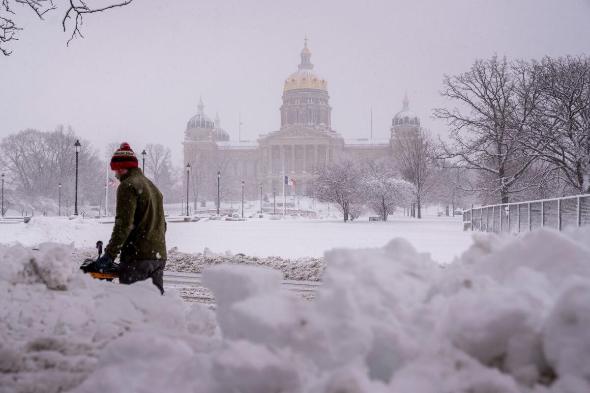The Iowa State Capitol Building is visible as Spud Glaser of Carlisle, Iowa, ploughs the sidewalk in downtown Des Moines, Iowa, on Tuesday as a winter snow storm hits the state. — AP