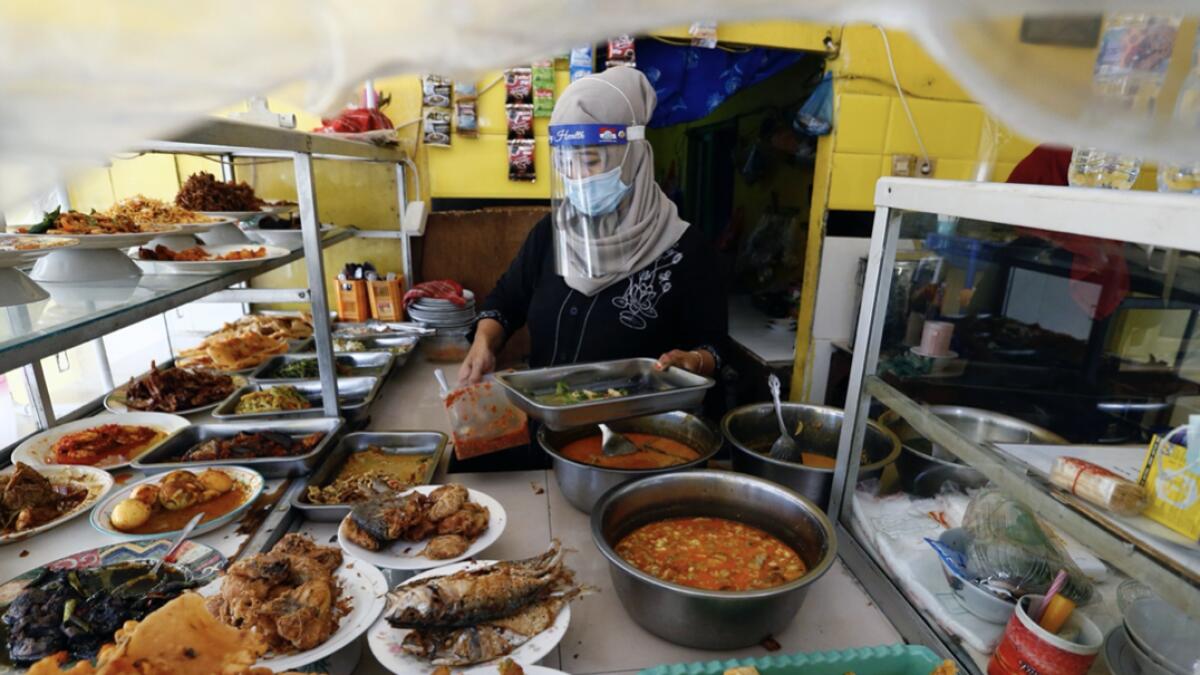 A woman wearing a protective face mask and a face shield works at a food stall, as the government eases the restrictions imposed due to the outbreak of the coronavirus disease (Covid-19), in Jakarta, Indonesia. Photo: Reuters
