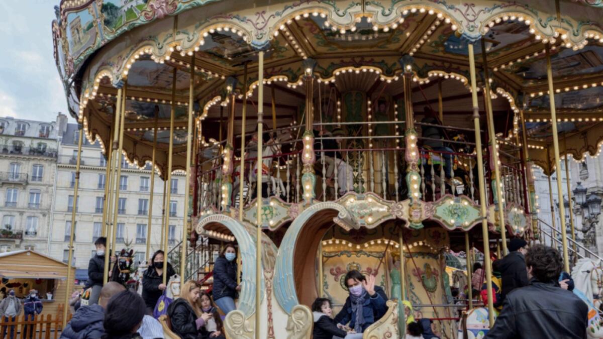 People wearing face masks to prevent the spread of the Covid-19, sit on a carousel in Paris. — AP