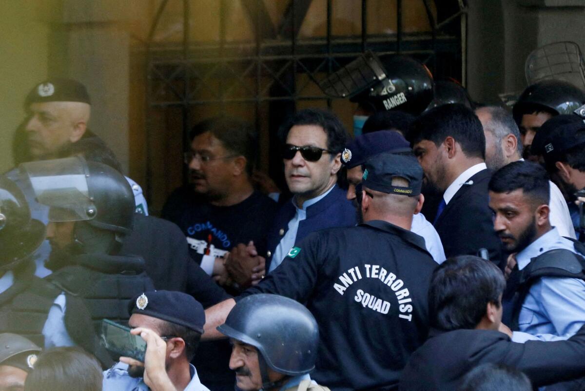 FILE. Security officers escort Pakistan's former Prime Minister Imran Khan, as he appeared in Islamabad High Court. Photo: Reuters