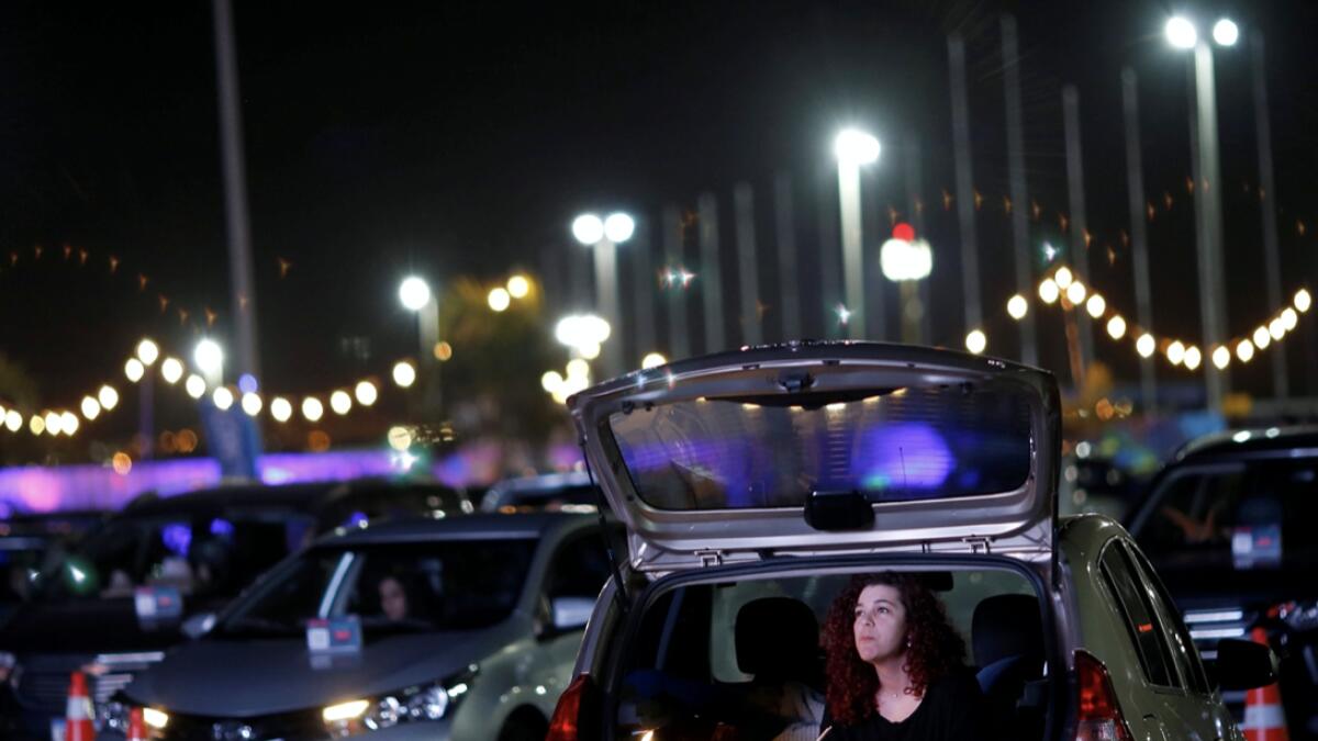 A woman inside her car attends a performance of the Brasilia Philharmonic Orchestra during the inauguration of the drive-in movie theatre at the parking lot of President Juscelino Kubitschek International Airport Park, amid the spread of the coronavirus disease (Covid-19), in Brasilia, Brazil. Photo: Reuters