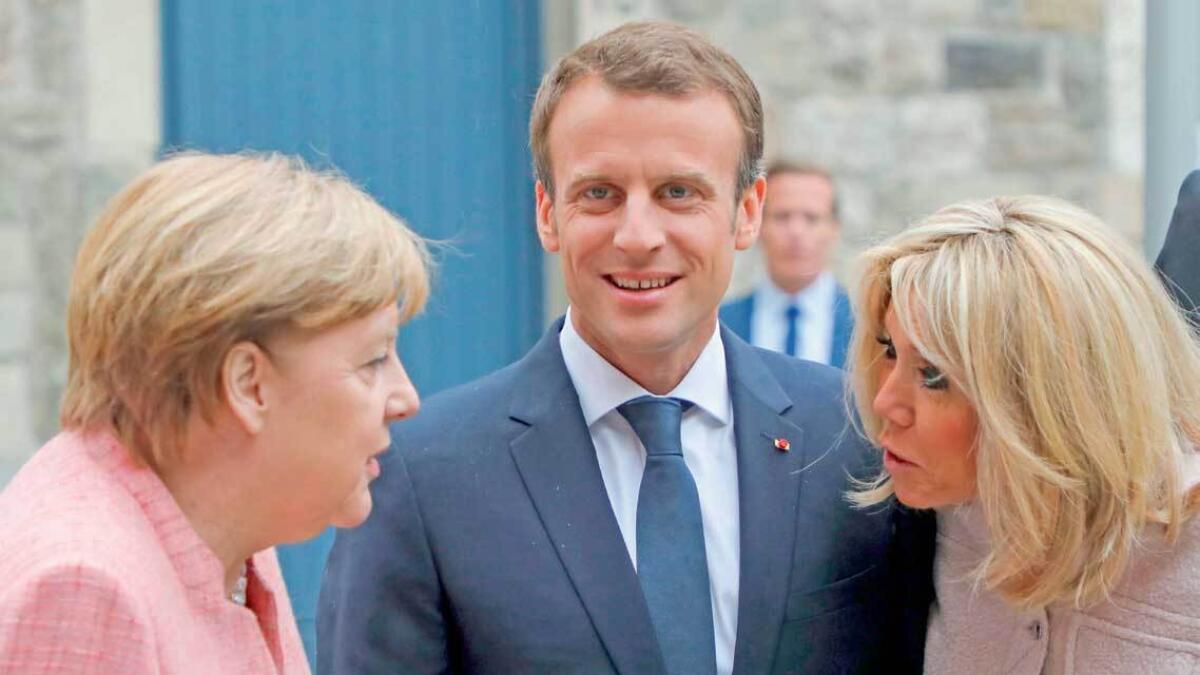 German Chancellor Angela Merkel (L), French President Emmanuel Macron and his wife Brigitte Macron talk as they arrive to attend mass at the Cathedral of Aachen on Thursday. — AFP