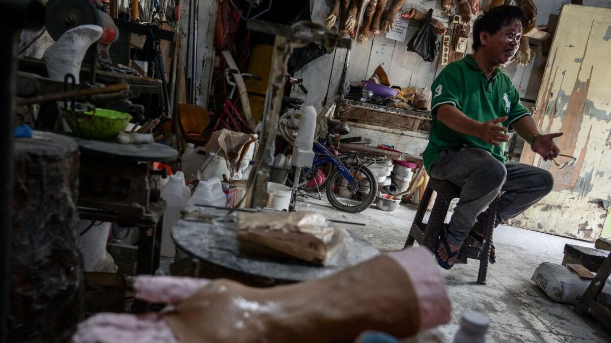 Former leprosy patient Ali Saga speaking about his experience in becoming a self-taught maker of prosthetic legs and hands inside his workshop in Tangerang. — AFP