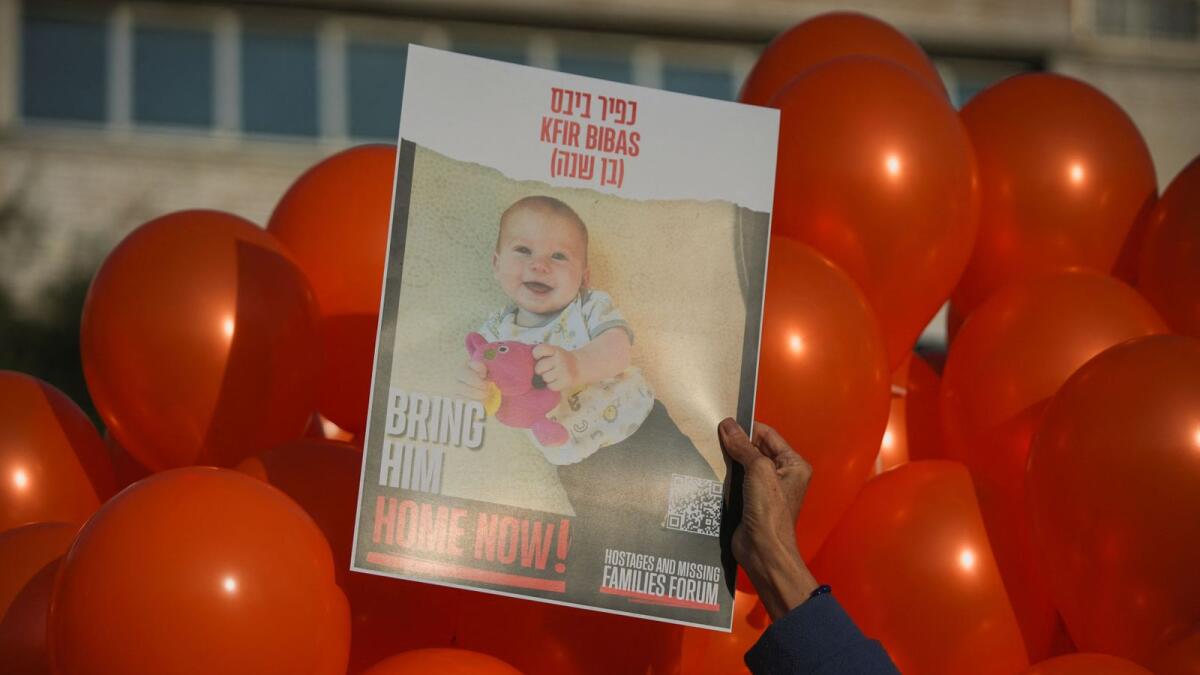 A person holds a poster depicting Kfir Bibas, who was taken hostage along with his brother and parents on October 7, as his relatives and supporters mark his first birthday  at an event in Tel Aviv. — Reuters