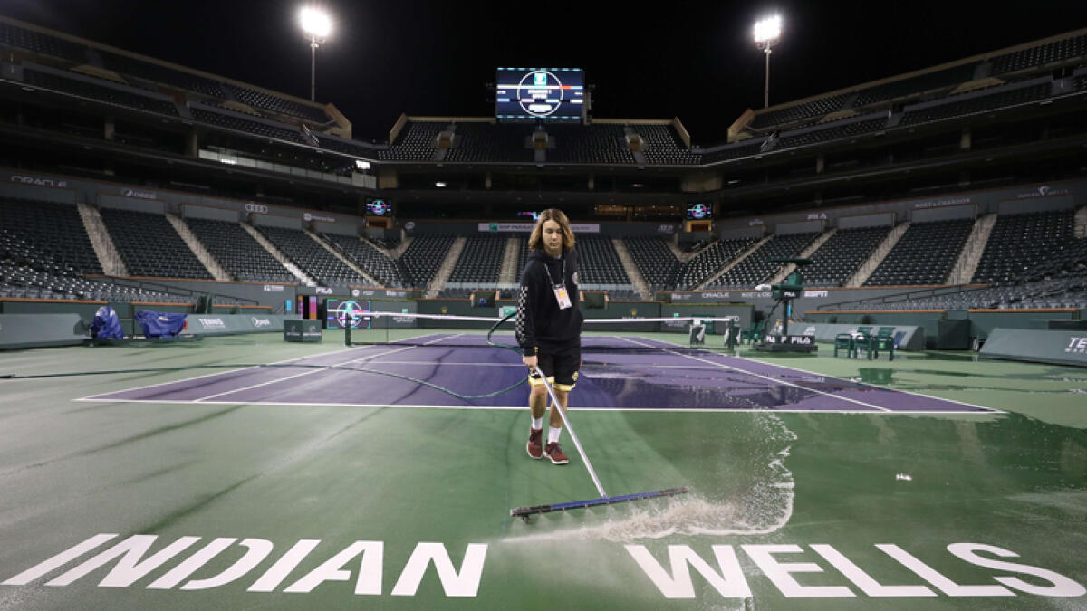 Courtmaster Jeffrey Brooker cleans the Centre Court at the Indian Wells Tennis Garden a day before the tournament was cancelled. - AFP