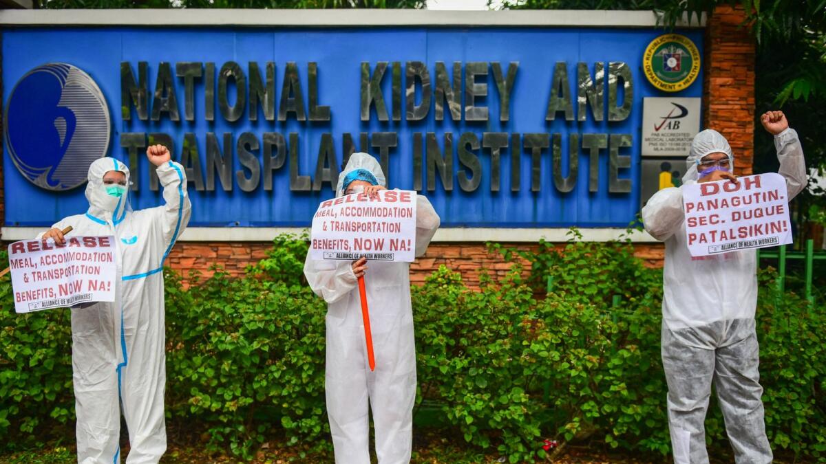 Health workers in protective suits demonstrate, calling the government to release their allowances amid rising covid-19 infections, in front of a hospital in Manila. Photo: AFP