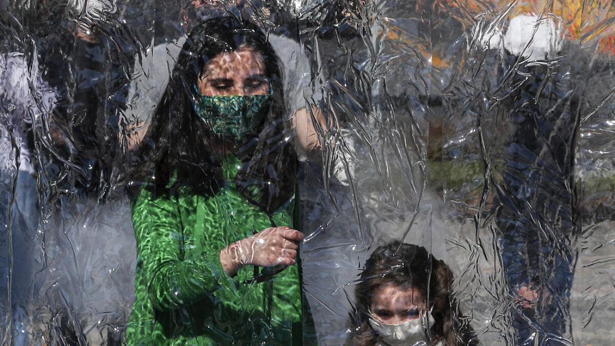A woman and child wearing protective face masks prepare to enter a decontamination chamber as a precaution against the spread of the new coronavirus, at the entrance of Araucano Park in Las Condes borough of Santiago Chile. Photo: AP