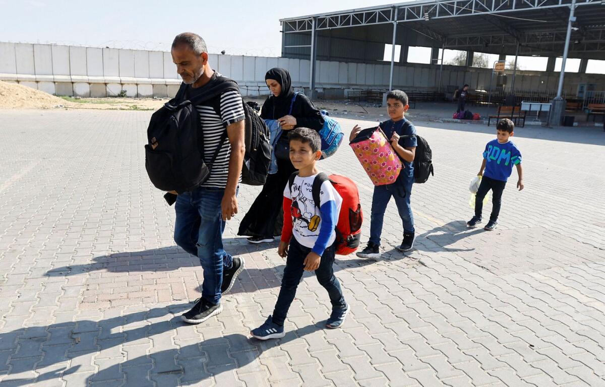 Family members carry their luggage as Palestinians, including foreign passport holders, wait at Rafah border crossing after evacuations were suspended following an Israeli strike on an ambulance, in Rafah in the southern Gaza Strip, November 5, 2023. Photo: Reuters