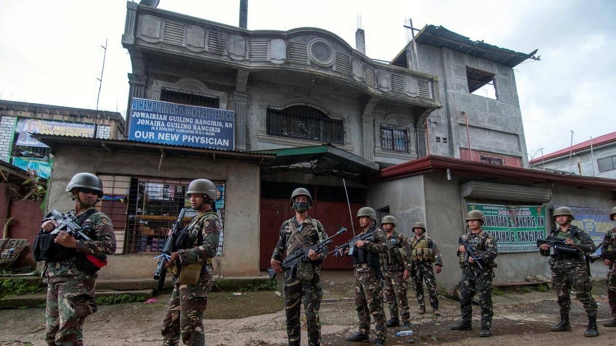 A joint group of police and military forces stands guard while conducting a house to house search as part of clearing operations in different sections of Marawi city, Philippines