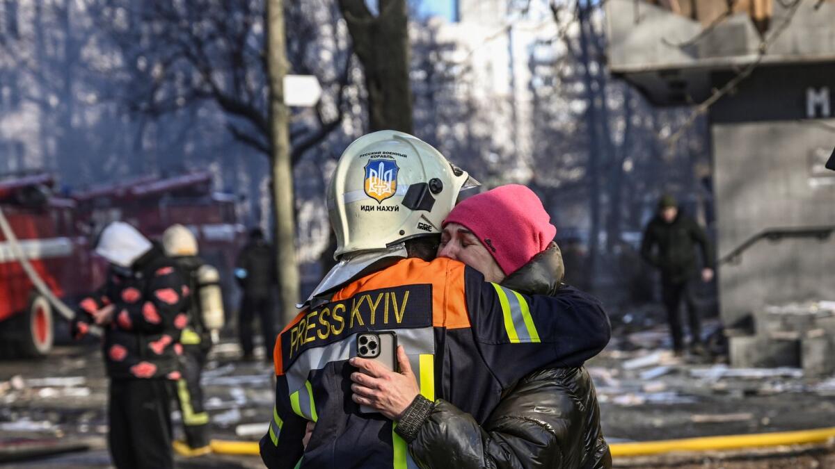 A fireman embraces a woman outside a damaged apartment building in Kyiv on March 15, 2022, after strikes on residential areas killed at least two people, Ukraine emergency services said as Russian troops intensified their attacks on the Ukrainian capital. Photo: AFP