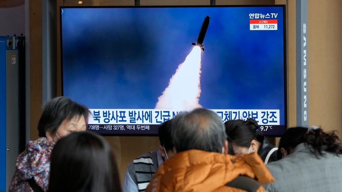 People stand by a TV screen showing a file image of North Korea's rocket launch during a news program on March. (AP)