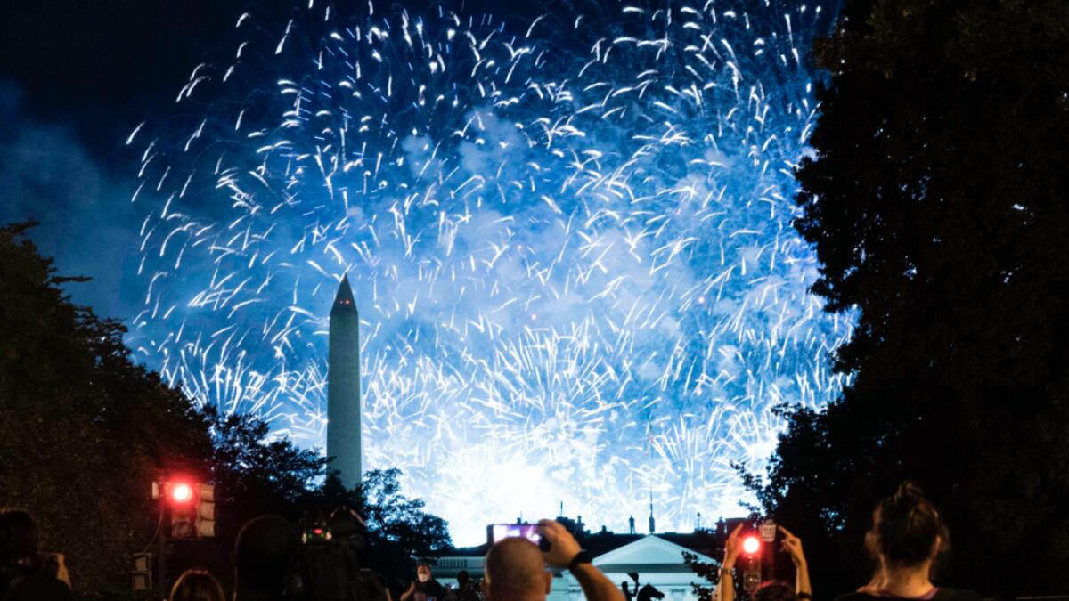 Fireworks paint the sky above the obelisk of the Washington Monument while demonstrators, protesting the nomination of Donald Trump, watch at Black Lives Matter plaza across from the White House in Washington, DC.  Photo:  AFP