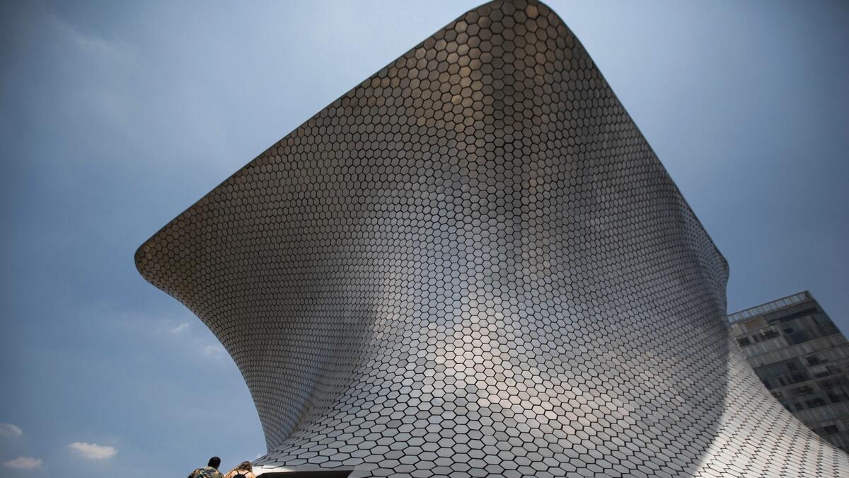 A couple climbs the stairs to the Soumaya Museum that opened today after almost five months of being closed to the public as a measure to control the spread of new coronavirus, in Mexico City.  Photo: AP