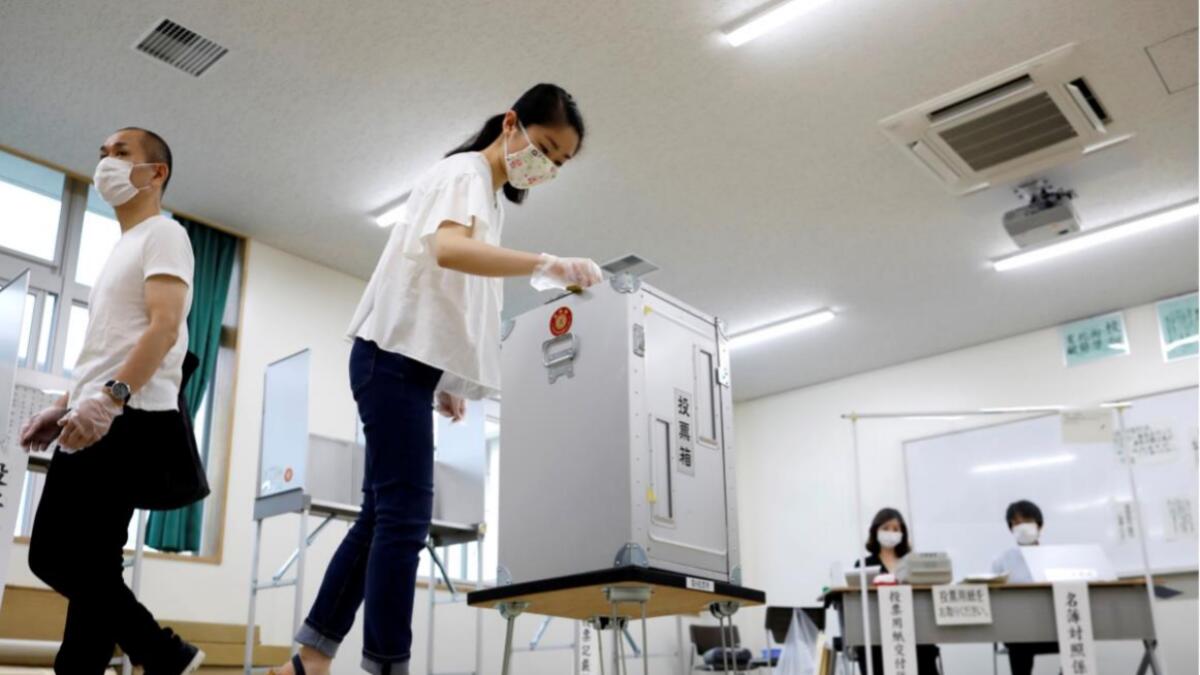 A voter wearing a protective face mask and vinyl gloves casts a ballot amid the coronavirus disease (Covid-19) outbreak, at a voting station for the Tokyo Governor election in Tokyo, Japan on July 5, 2020. Reuters
