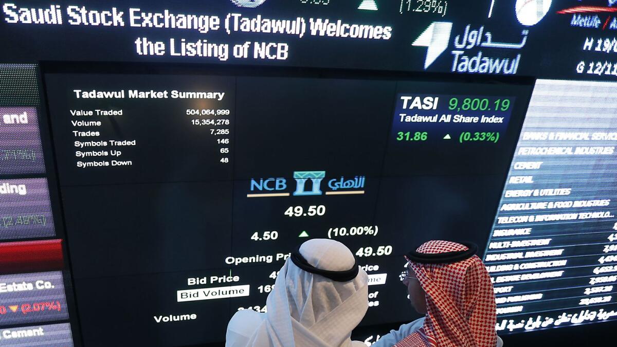 Saudi investors monitor stocks. Saudi Arabia’s benchmark index gave up early gains to finish flat. — File photo