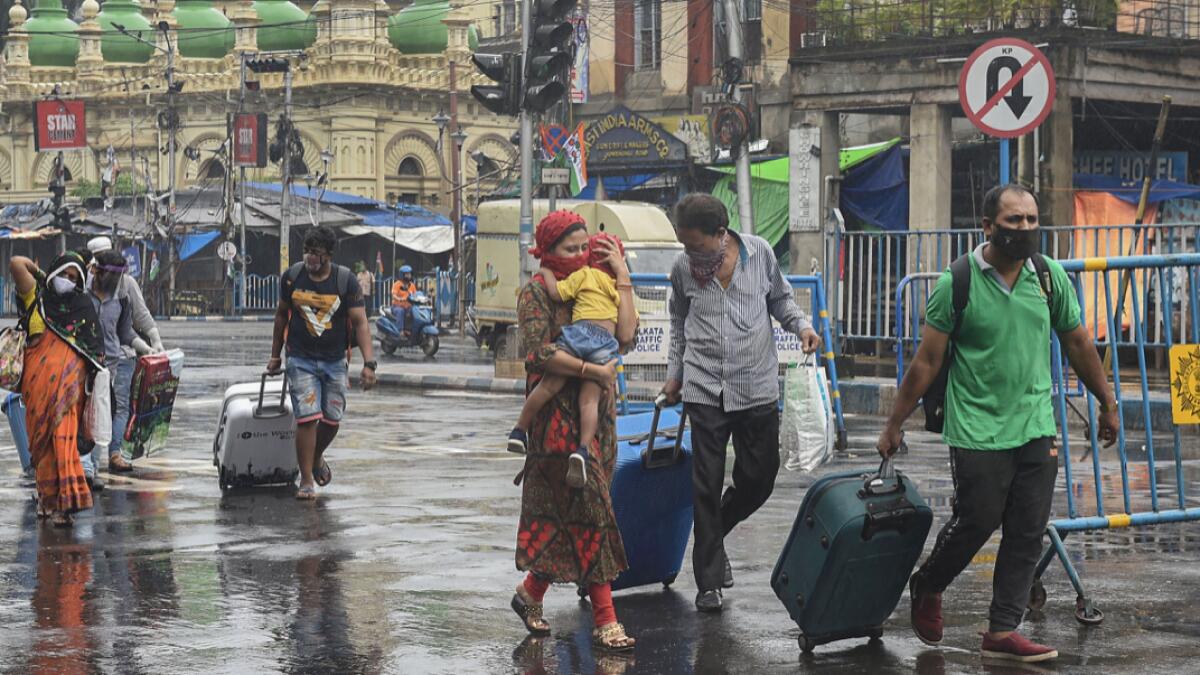 Passengers with their luggage walk on a street during the weekly two-day complete lockdown, to curb the spread of coronavirus disease, in Kolkata. Photo: PTI