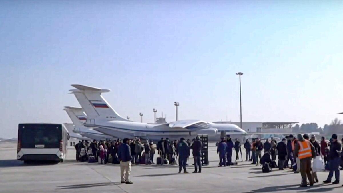 Passengers gather to board the Russian Military Il-76 cargo planes at the airport in Kabul. — AP