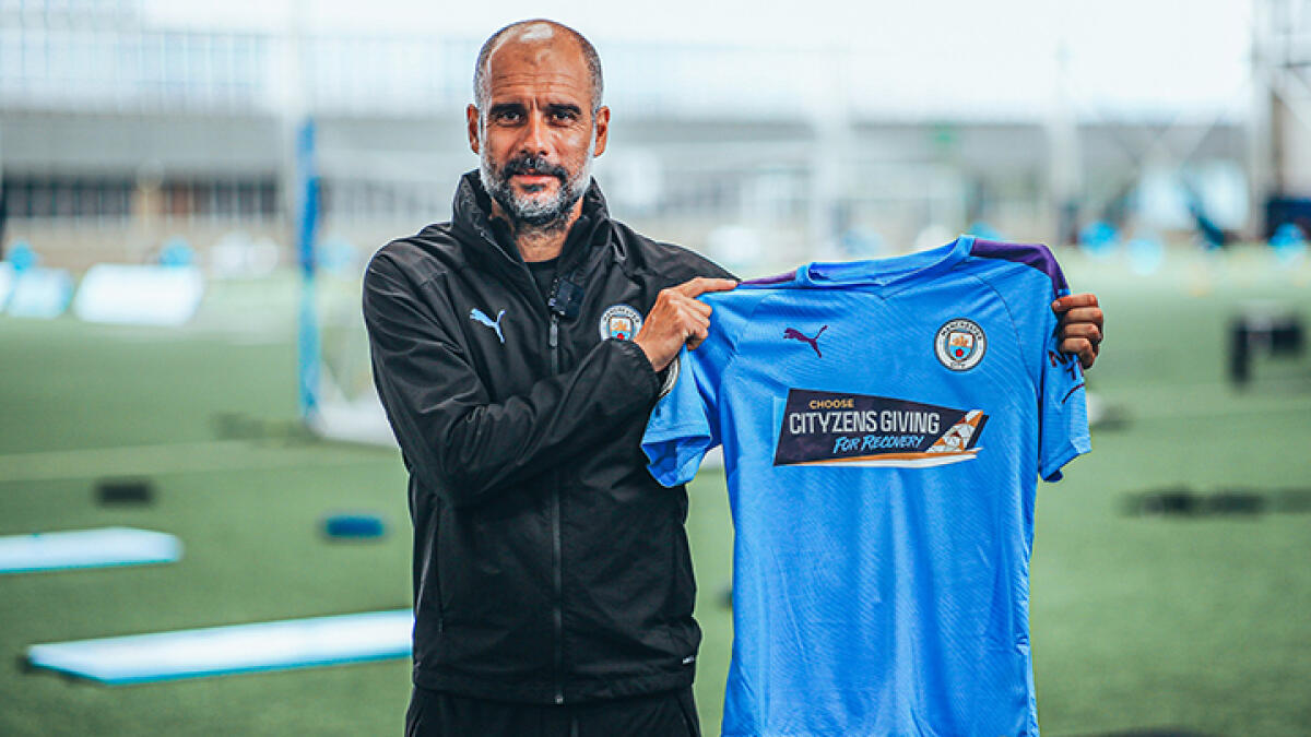 Manchester City Pep Guardiola displays the team's bespoke match-day jersey. -- Supplied photo