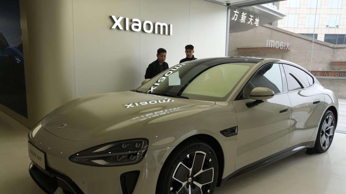 Visitors to the Xiaomi Automobile flagship store look at the Xiaomi SU7 electric car. — AP