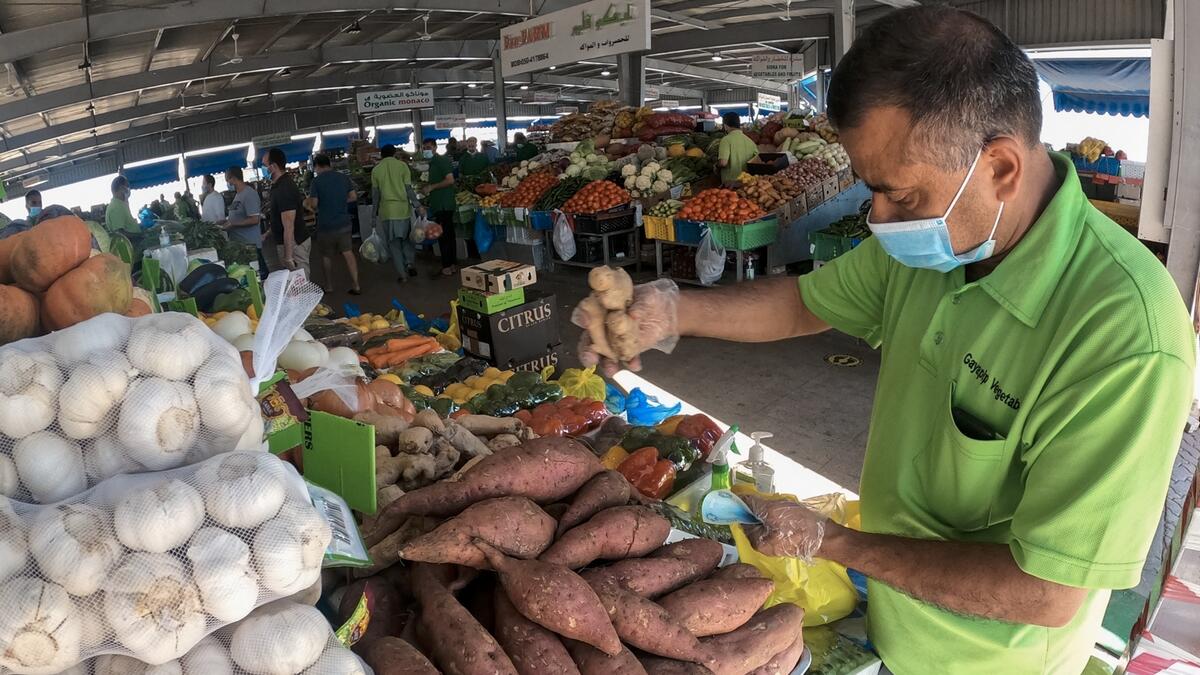 A vegetable seller wearing mask and gloves as a means of protection against the spread of the coronavirus, serves a customer at the Fruits and Vegetable market in Abu Dhabi. Photo: Ryan Lim/Khaleej Times