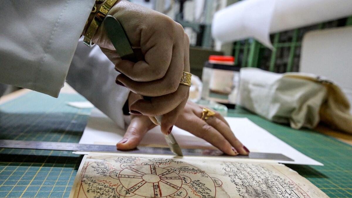 A conservator restores a manuscript at the Iraqi Manuscript House's resoration lab in Iraq's capital Baghdad on December 6, 2022. — AFP