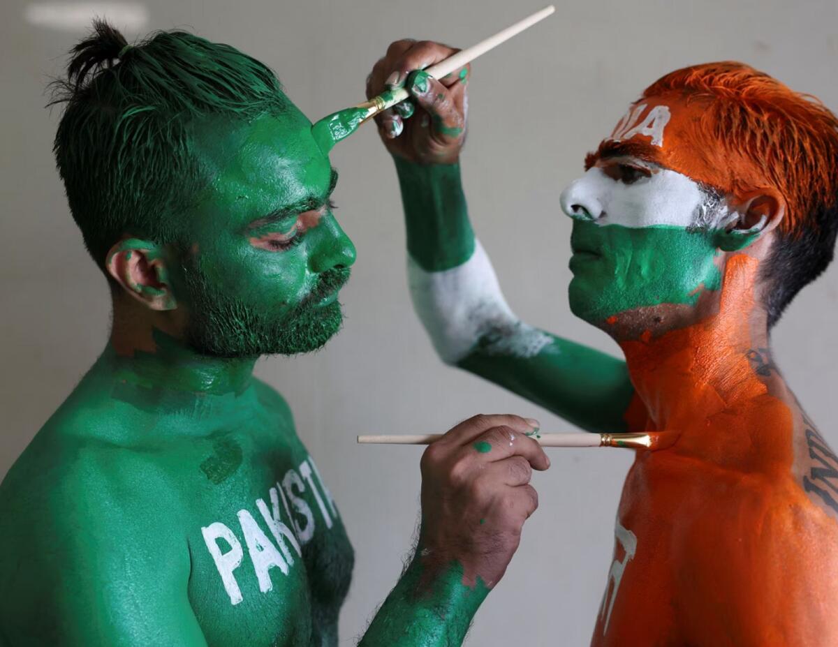 Fans, Arun Haryani (right) and Anil Advani paint their bodies in the Indian and Pakistani national flag colours, ahead of the match in Ahmedabad. — Reuters