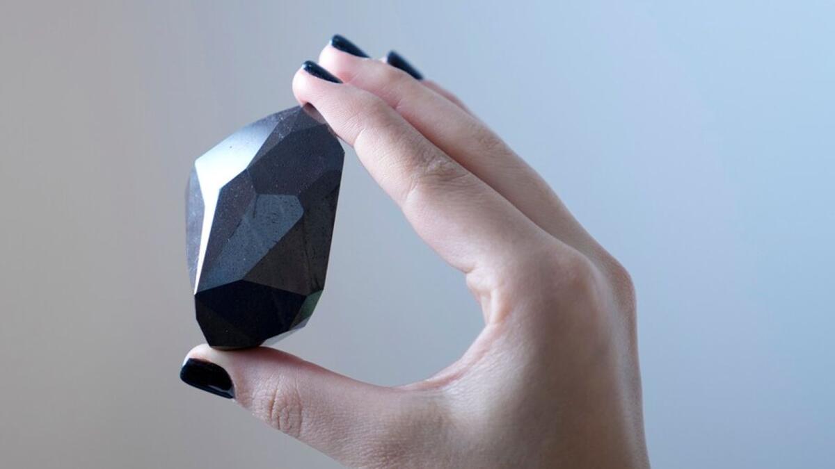 An employee of Sotheby’s Dubai presents a 555.55 Carat Black Diamond “The Enigma” to be auctioned at Sotheby’s Dubai gallery, in Dubai, United Arab Emirates, Monday, Jan. 17, 2022. (Photo: AP)