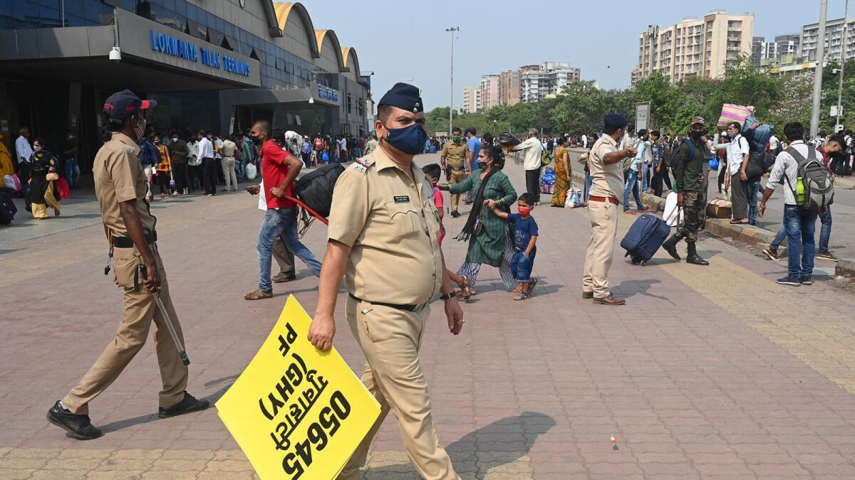 A policeman holds a board to guide passengers outside a railway complex in Mumbai amidst rising Covid-19 coronavirus cases. Photo: AFP