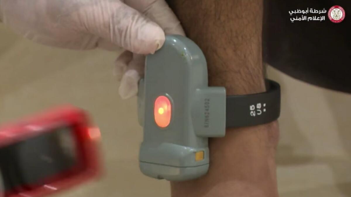 A screen grab from a video shared by the Abu Dhabi Police shows an electronic tagging device being fixed on an offender.