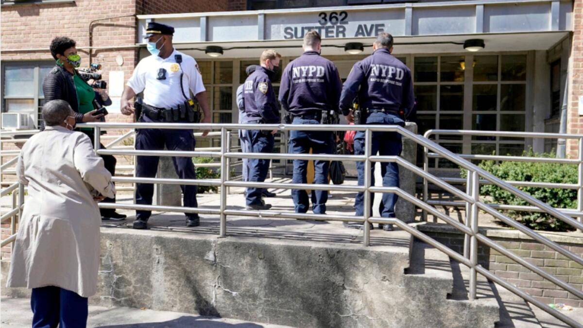 Police officers and community leaders stand outside the building where a man shot the mother of his child and two of her daughters dead before turning the gun on himself. — AP