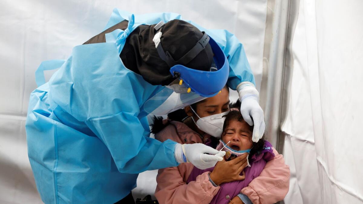 A healthcare worker wearing personal protective equipment (PPE) takes a swab sample from a child to be tested for the coronavirus disease (COVID-19) in Mexico City, Mexico November 20, 2020.
