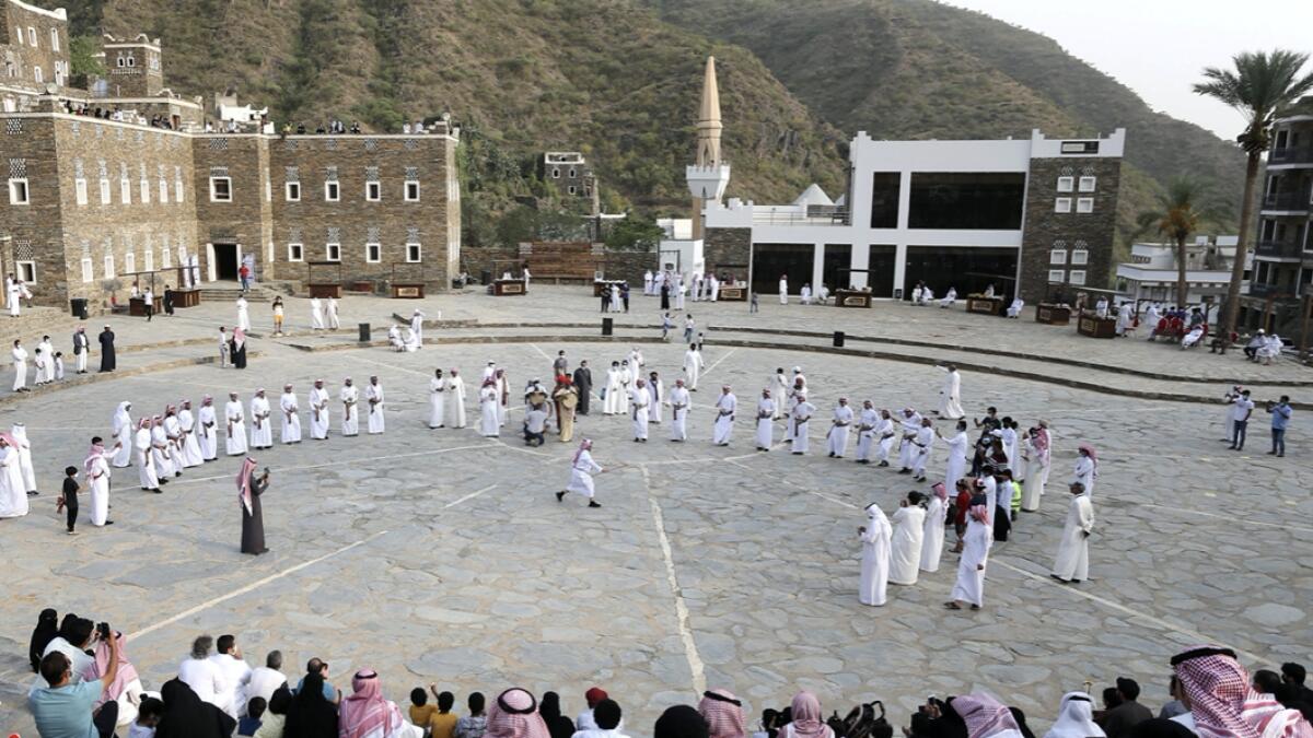 Tourists watch Saudi men perform a traditional folk dance at the cultural village of Rijal Almaa in the outskirts of Abha, Saudi Arabia. Photo: Reuters