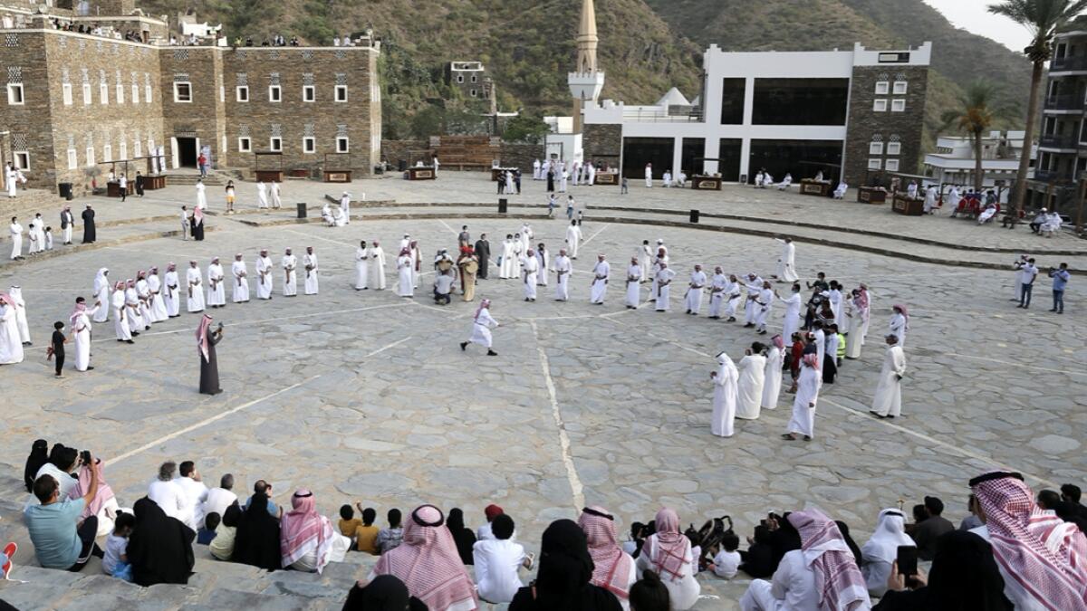Tourists watch Saudi men perform a traditional folk dance at the cultural village of Rijal Almaa in the outskirts of Abha, Saudi Arabia. Photo: Reuters