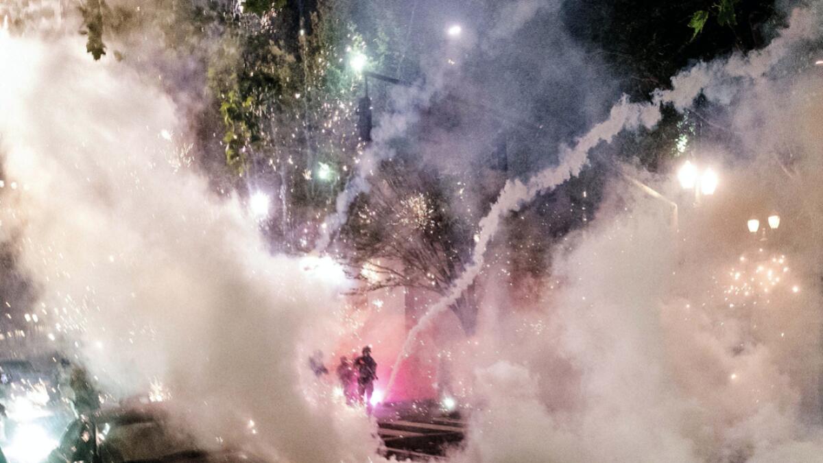 Smoke fills the sky as federal officers try to disperse Black Lives Matter protesters, in Portland, Ore.  A federal judge is hearing arguments on Oregon's request for a restraining order against federal agents who have been sent to the state's largest city to quell protests that have spiraled into nightly clashes between authorities and demonstrators. Photo: AP