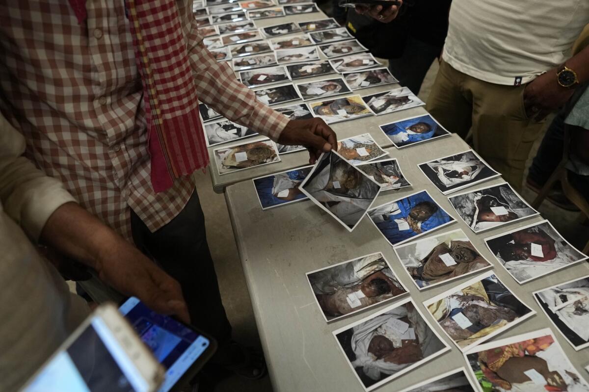 Relatives look at the photographs of unidentified bodies of passengers displayed for identification in Balasore district, Orissa, on June 4, 2023. Photo: AP