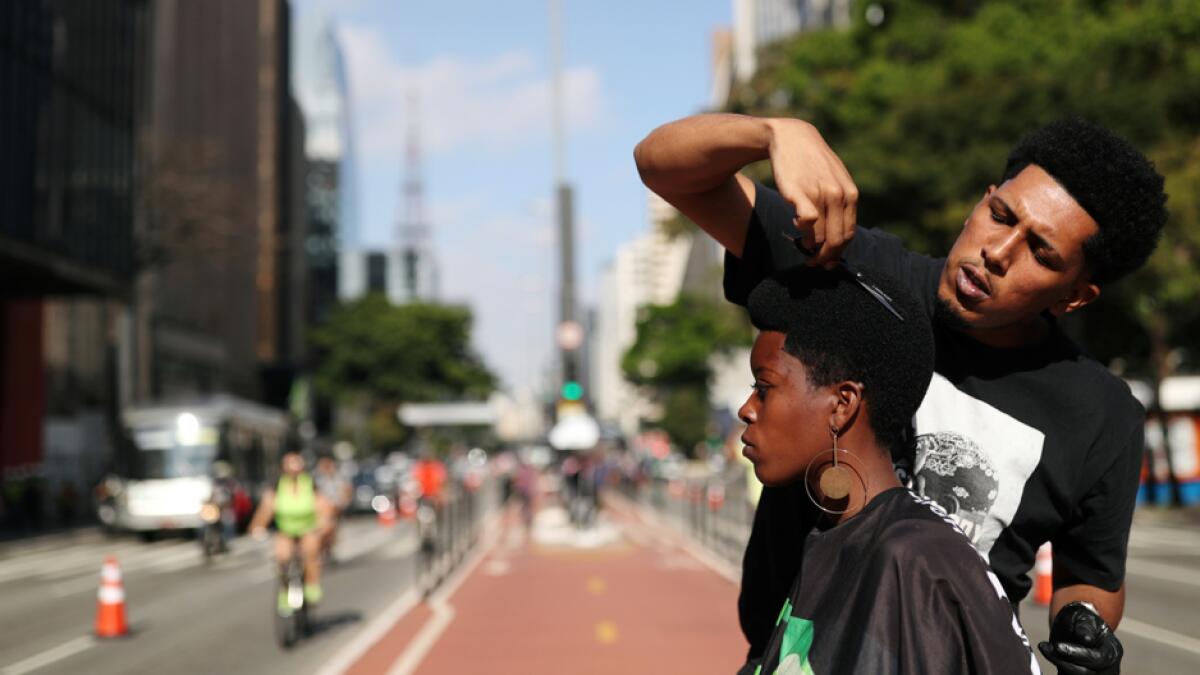 Hairdresser Lucas Brown cuts Larissa Andrade's hair in the middle of Paulista Avenue as part of a project to exalt and stimulate Black culture in Sao Paulo, Brazil. Photo: Reuters