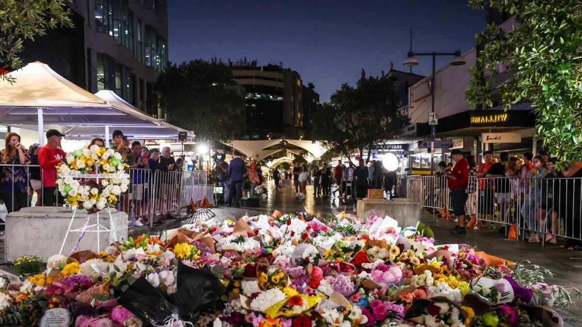 Members of the public look at flowers placed outside the Westfield Bondi Junction shopping mall in Sydney on Sunday, the day after a 40-year-old knifeman with mental illness roamed the packed shopping centre killing six people and seriously wounding a dozen others.  — AFP