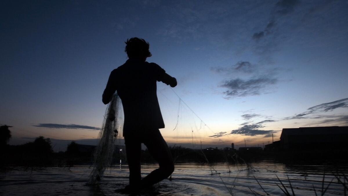 A construction worker is silhouetted as he pulls his fishing net at the flooded land following recent rain in Chres village on the outskirts of Phnom Penh, Cambodia. Photo: AP