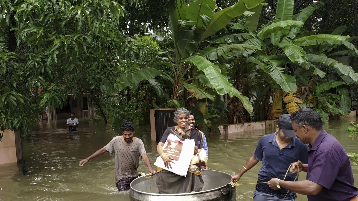 An elderly woman is rescued in a cooking utensil after her home was flooded in Thrissur, Kerala state, India.- AP