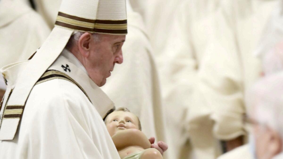 Pope Francis holds a figurine of baby Jesus during the Christmas Eve mass at St Peter's basilica in the Vatican. — AFP
