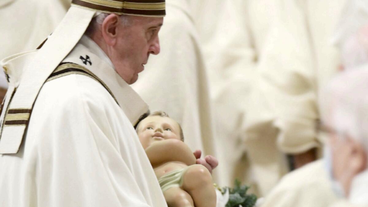 Pope Francis holds a figurine of baby Jesus during the Christmas Eve mass at St Peter's basilica in the Vatican. — AFP