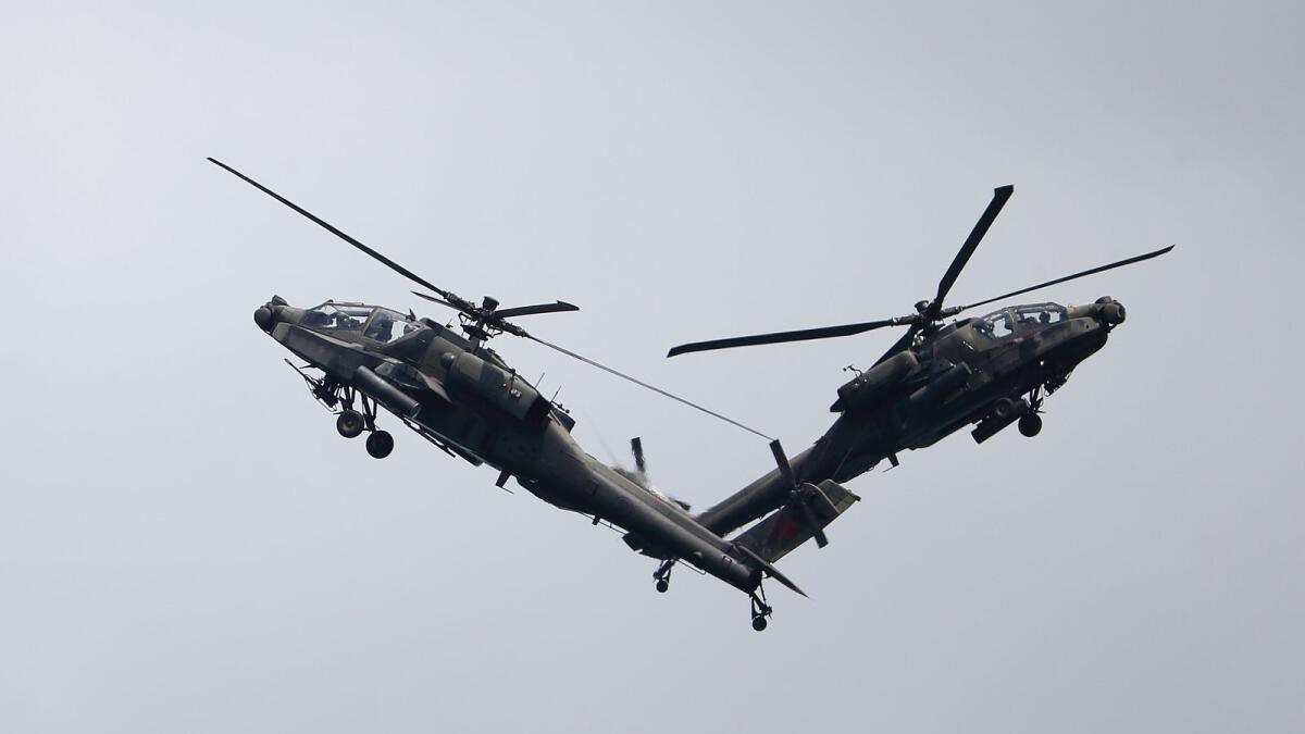 A pair of Republic of Singapore Air Force (RSAF) AH-64D Apache attack helicopters perform aerial maneuvers during the Singapore Airshow 2022 at Changi Exhibition Centre in Singapore on Tuesday. — AP