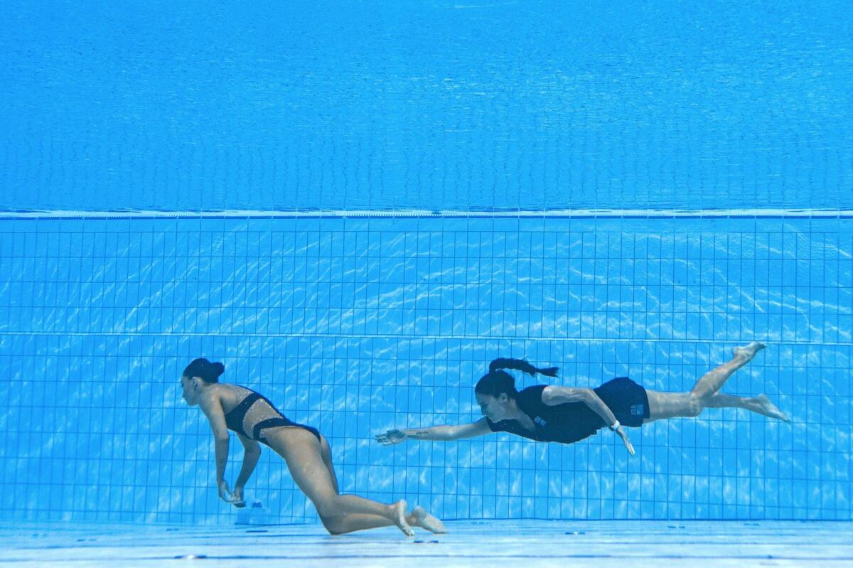USA's coach Andrea Fuentes (R) swims to recover USA's Anita Alvarez (L), from the bottom of the pool. (Photo: AFP)